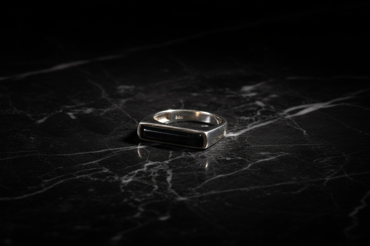 Anillo ónix rectangular sobre mármol negro