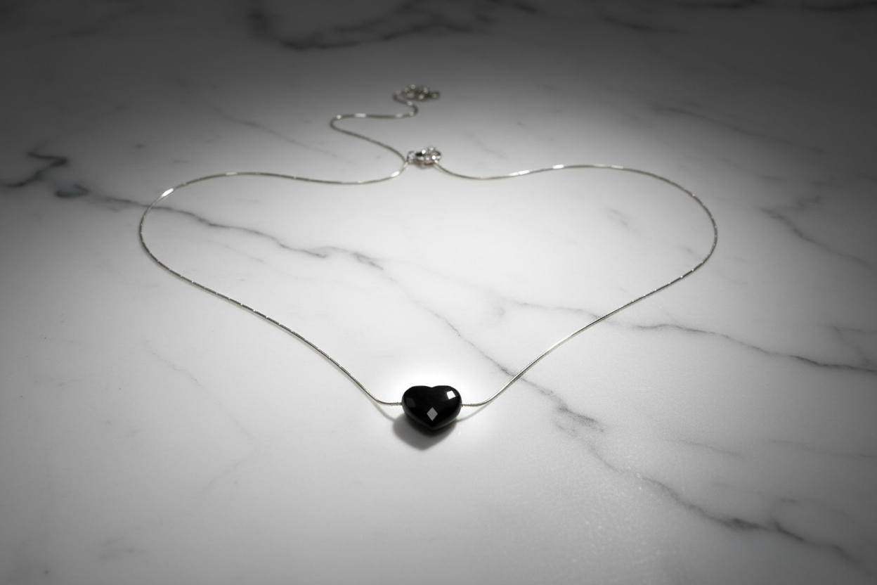 Collar corazón negro sobre mármol blanco