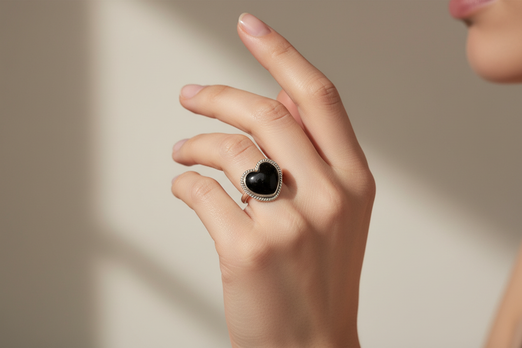 Mano femenina con anillo corazón negro